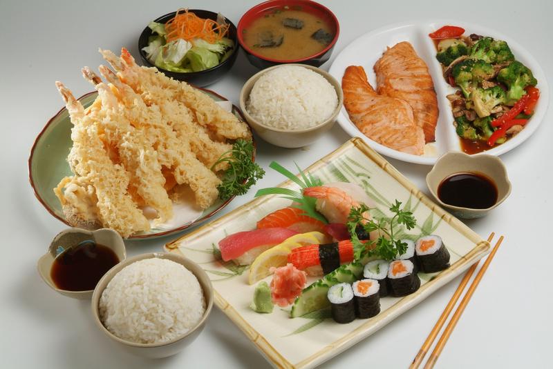 A plate of tempura, a plate of maki & nigiri, a plate of teriyaki salmon & mixed vegetables, with bowls of miso soup, rice & soy sauce
